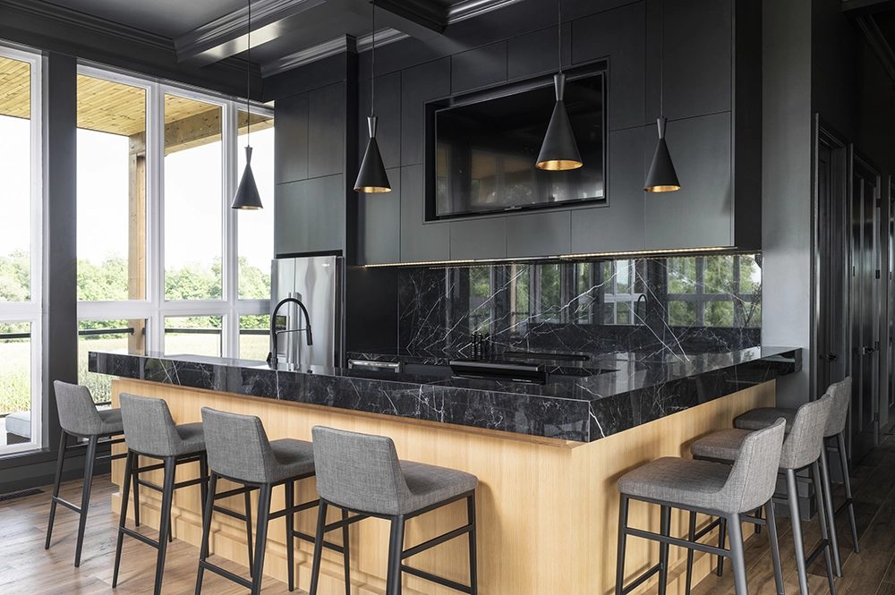 A dark kitchen with a marble-look bar and wood-wrapped island